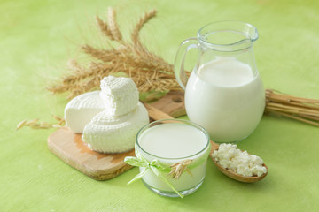 Shavuot concept - dairy products and wheat on green wood background