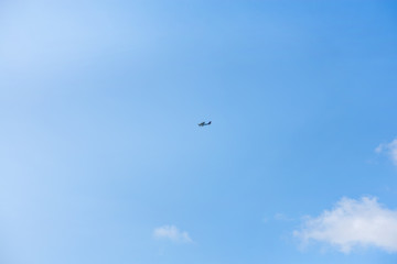 Military helicopter flying in the sky over a city and crowded event, taking photos, filming from above on clear blue sky background. An Isolated helicopter. Team of rescuers searching for lost people