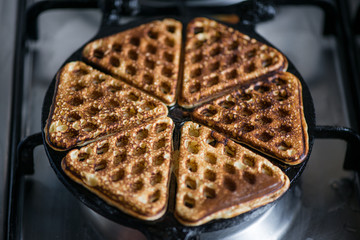 Just cooked, delicious, tasty, hot yogurt pancakes on waffle iron on fire stove in kitchen. Dinner is ready. Sweet golden brown waffles ready to be eaten