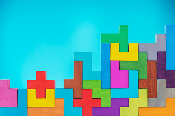 Different colorful shapes wooden blocks on blue background. Geometric shapes in different colors, top view.  Copy space.