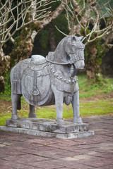 Fototapeta na wymiar Vietnam, Hue. Stone statue of horse from the royal escort that accompanies the emperor in the other world at Imperial Minh Mang Tomb on the Salutation Court