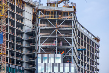 New residential and office block buildings being constructed. Industrial building site. Workers putting windows in under construction skyscraper