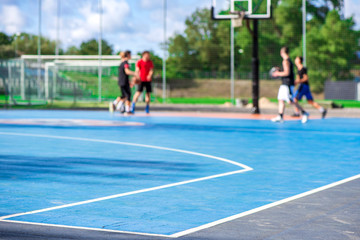 Abstract, blurry background of boys playing basketball in outdoor basketball court in park