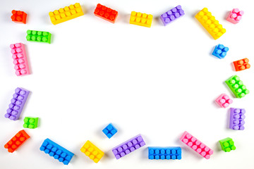Colorful plastic construction blocks on white background as kids toys frame