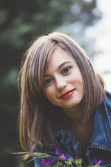 Naklejka premium Happy teen girl in the forest with flowers