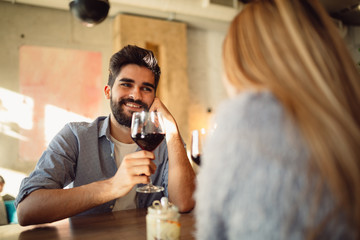 Young handsome man is drinking wine with his girlfriend at cafe