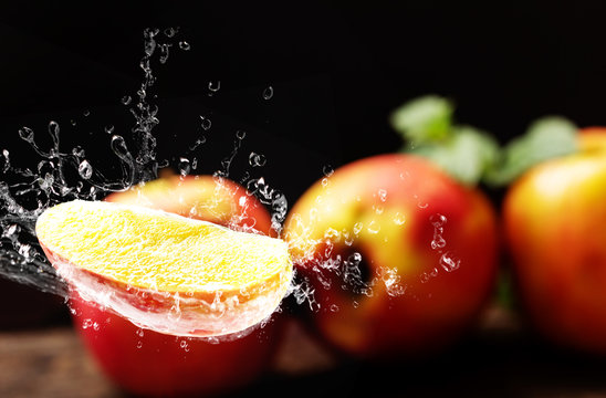 Apple with water splashing against dark background