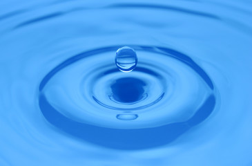 Naklejka na ściany i meble Water drop on a blue surface.