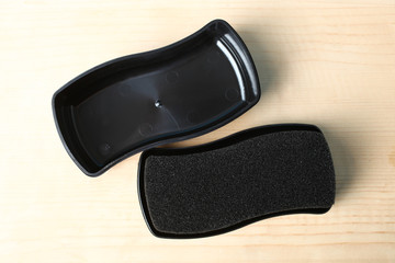 Black foam rubber brush for cleaning and polishing shoes on a wooden background.