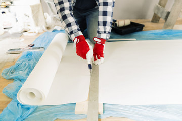 Handyman, worker measuring wallpaper to cut. Home renovation and repair concept