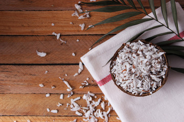 fresh natural coconut shavings, palm leaves, half coconut on the background of wood. 