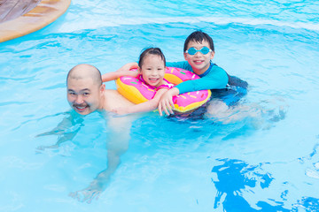 Fototapeta na wymiar Happy Asian family playing together in swimming pool