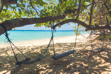 Swing and hammock on the beach with turquoise blue sea in background