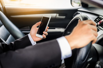 Attractive handsome young businessman using mobile smart phone in car