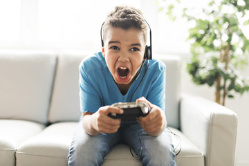 black boy play video game on sofa with headset