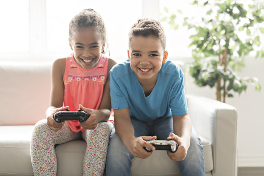 brother and sister play video game on sofa