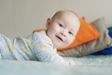 The little boy is lying on the bed