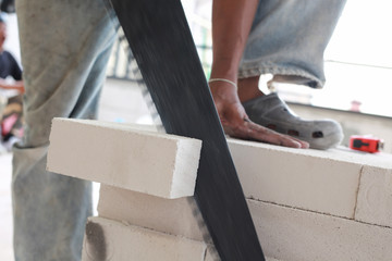 Worker cutting bricks with crosscut saw.