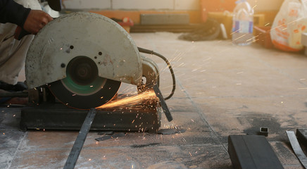 Close-up of worker cutting metal with grinder. Sparks while grinding iron.
