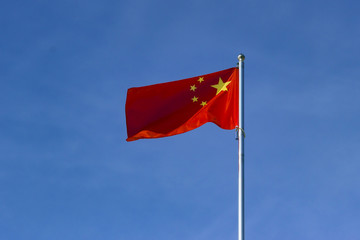 Chinese flag waving in the wind against the cloudless sky background