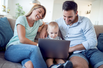 Obraz premium Happy family using laptop together on sofa