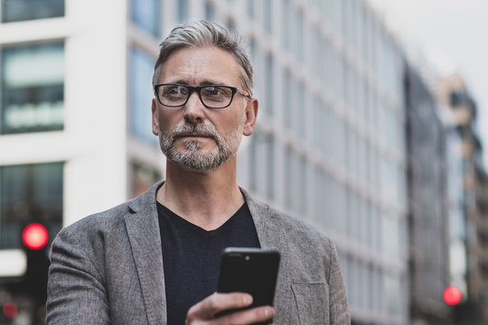 Mature male walking and on on smartphone in city