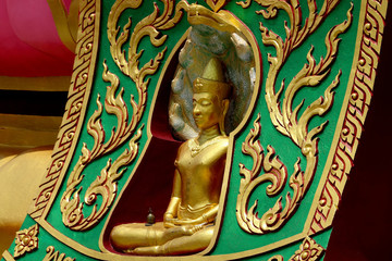 A close up shot of a small golden Buddha statue surrounded by beautiful decoration.