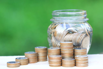 Saving money for prepare in future concept, Stack of coins money and glass bottle on natural green background