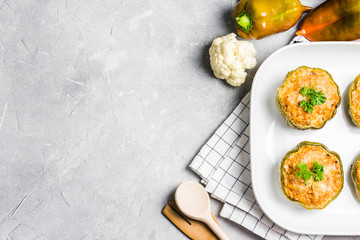 Healthy quinoa stuffed peppers in baking dish on light concrete background. Top view, copy space.