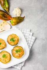 Spicy stuffed peppers in baking dish on light concrete background. Top view, copy space.