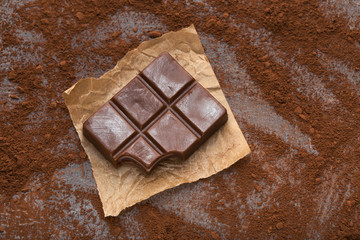 Crushed chocolate bar pieces and cocoa on gray background