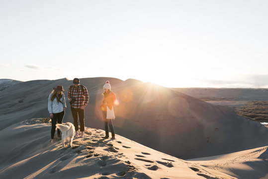 Friends with dog on sand dune, Bruneau, Idaho, USA