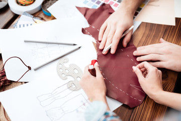 Top view two fashion designers making cutout.