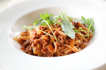 spaghetti Bolognese with minced beef and tomato sauce garnished with parmesan cheese and basil , Italian food
