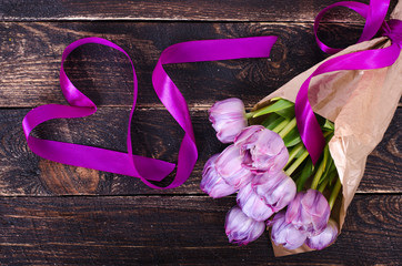 Valentines background. Violet tulips, tape formed heart on wooden background. 