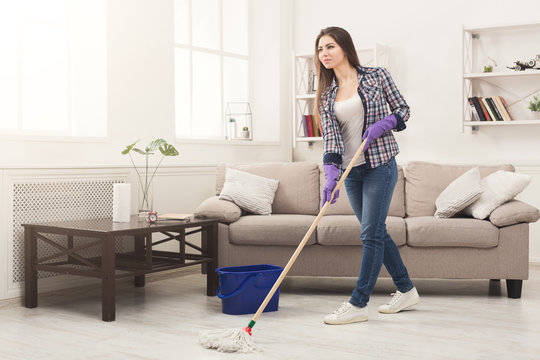 Young woman cleaning house with mop