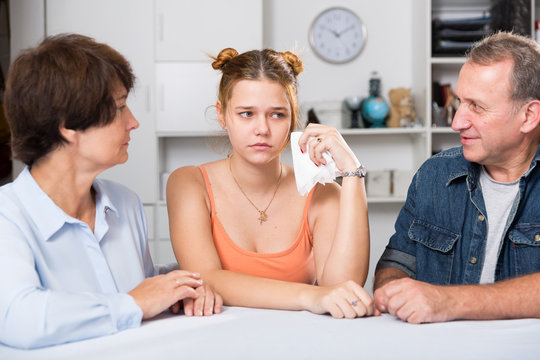 Parents are comforting the upset adult daughter at the table