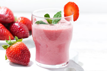 refreshing strawberry milkshake on white table, closeup