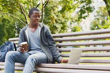 Fototapeta premium Sad young man using laptop outdoors