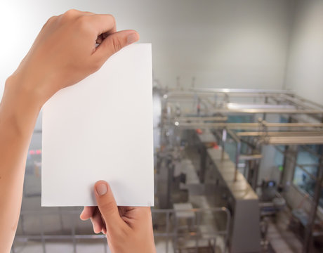 Hand hold blank notepad with space for text,Manufacturing factory blurred