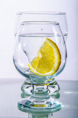 two glasses of water and lemon on a white background