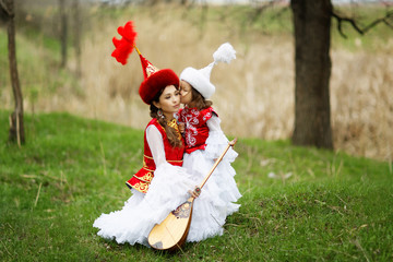 Kazakh people in national costumes. Woman and daughter in the park