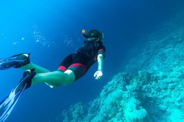 Girl in snorkeling gear dives into the sea