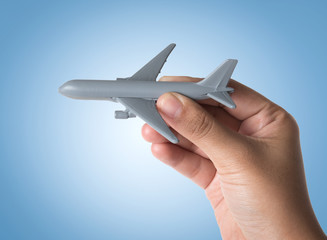 Hand holding miniature airplane on blue background