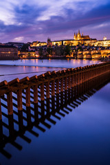 Fototapeta na wymiar Beleuchtete Karlsbrücke und Prager Burg bei Dämmerung mit Damm der Moldau