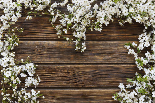 Close-up photo of Beautiful white Flowering Cherry Tree branchesheart shape on vintage wooden background.  Wedding, engagement or betrothal concept. Top view, greating card.