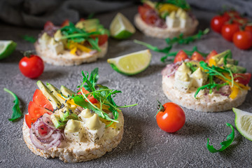 Bruschetta with tomato, avocado, herbs and arugula. Rustic background. Top view