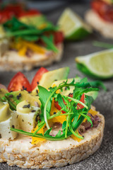 Bruschetta with tomato, avocado, herbs and arugula. Rustic background. Top view