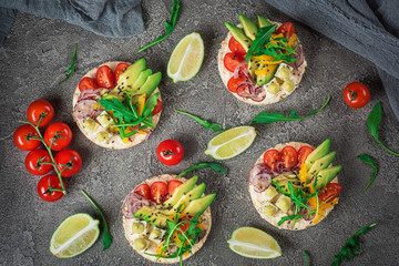 Bruschetta with tomato, avocado, herbs and arugula. Rustic background. Top view