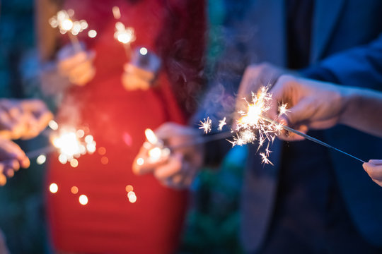 Young people holding fireworks at a party.